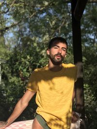 Portrait of young man standing against trees