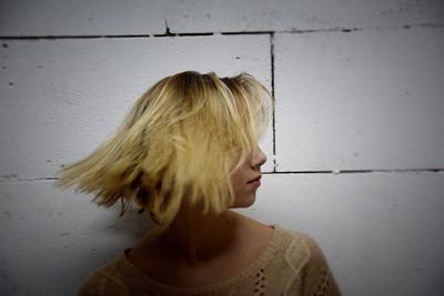 Close-up of young woman shaking head while standing by wall