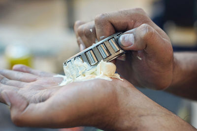 Cropped hands of mechanic holding tool and grease