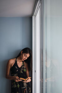 Young woman looking through window