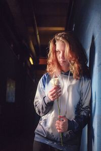 Young woman smiling while standing against wall