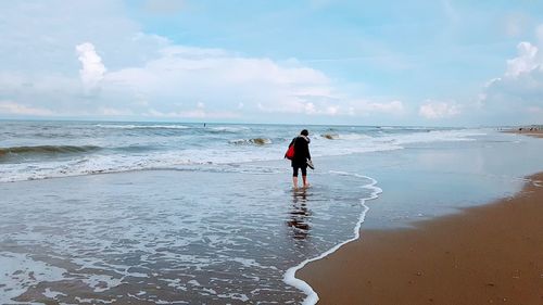 Rear view of man on beach against sky