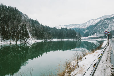 Scenic view of lake by snowcapped mountains against sky