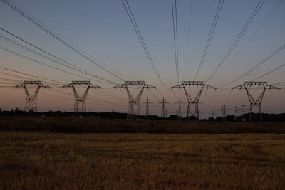 Electricity pylon on field against sky during sunset