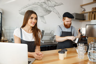 Young woman using phone while standing on table