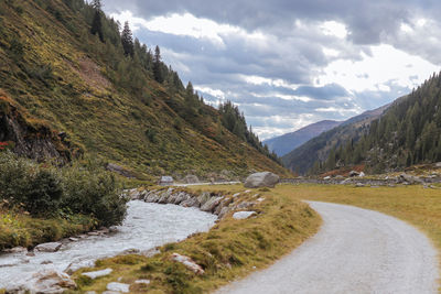 Scenic view of stream by mountains against sky