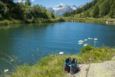 People sitting by lake against mountains