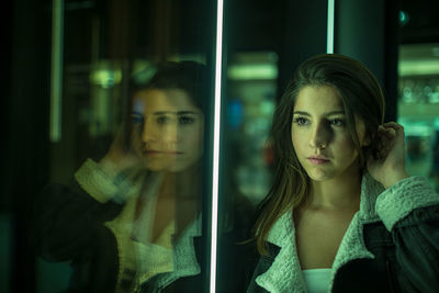 Portrait of young woman looking through glass window