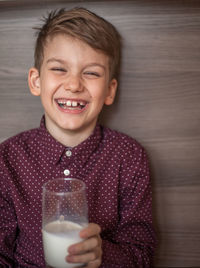 Portrait of laughing boy holding milk glass at home