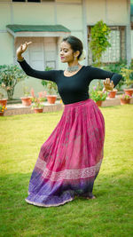 Young woman with arms raised on field