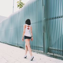 Rear view of young woman standing against wall