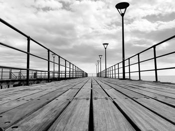 Surface level of pier on bridge over street against sky