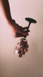 Upside down image of woman holding wineglass with corks against wall