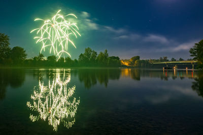 Firework display over lake against sky at night