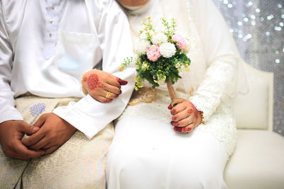Midsection of bride holding bouquet