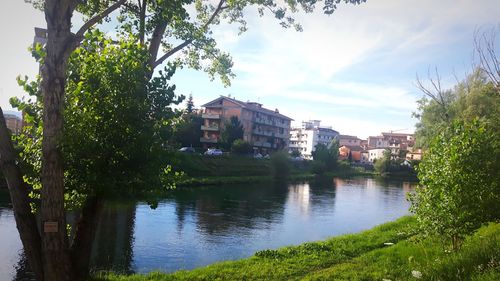River by buildings in city against sky