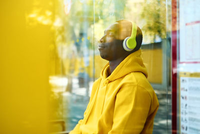 Portrait of young man looking away while standing on window