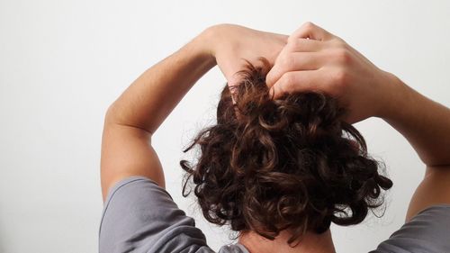 Rear view of man with hands in hair against white background