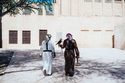 Traditionally dresses arabic man walking with a falcon next to the wind tower