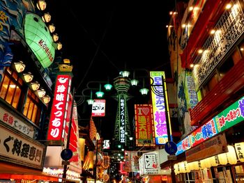 Low angle view of illuminated street amidst buildings at night