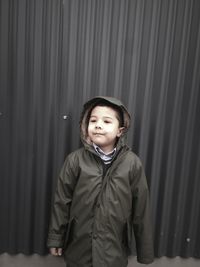 Cute boy looking away while standing against wall