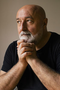 Thoughtful man with hands clasped day dreaming at home