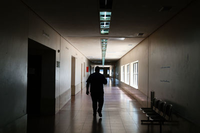 Rear view of man walking in illuminated building