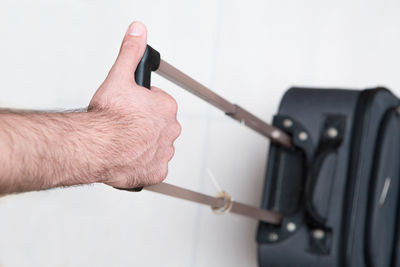 Cropped image of man pulling luggage at airport