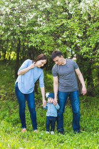 Full length of friends standing on grass against trees