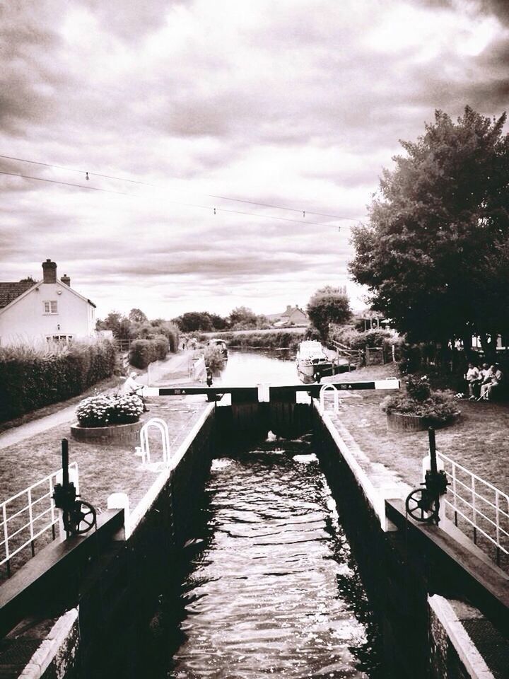 water, built structure, architecture, sky, building exterior, cloud - sky, canal, river, tree, waterfront, the way forward, railing, cloudy, reflection, bridge - man made structure, transportation, nature, weather, house, connection