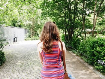 Rear view of young woman walking on footpath at park