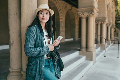 Portrait of woman standing against building