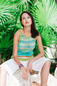 Portrait of young woman sitting against plants