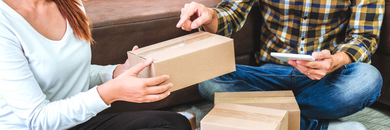 Midsection of couple holding camera in box