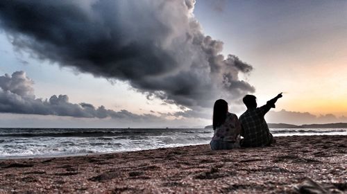 Silhouette people on beach against sky during sunset