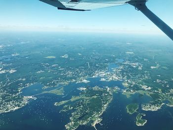 Aerial view of airplane wing over landscape against sky