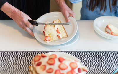 Cropped hands of woman serving sponge cake at table