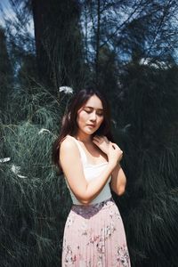 Portrait of beautiful young woman against plants