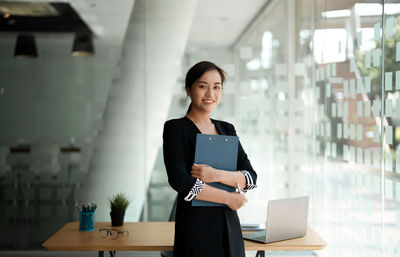 Portrait of young businesswoman standing in city