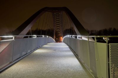 Illuminated footbridge against sky at night