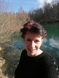 Portrait of smiling woman standing by water