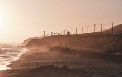 Scenic view of beach against clear sky during sunset