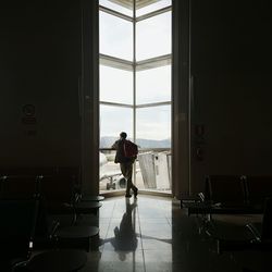 Rear view of standing by window at airport