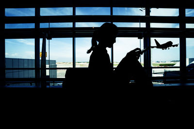 Silhouette people sitting at airport against sky
