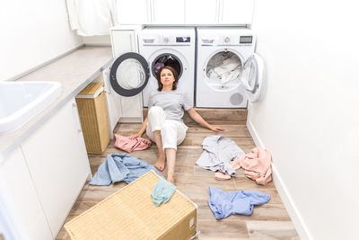 Portrait woman leaning on washing machine at home