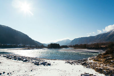 Scenic view of lake and mountains against blue sky