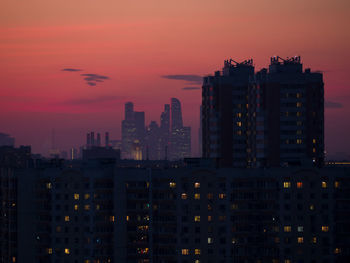 Illuminated buildings against romantic sky at sunset