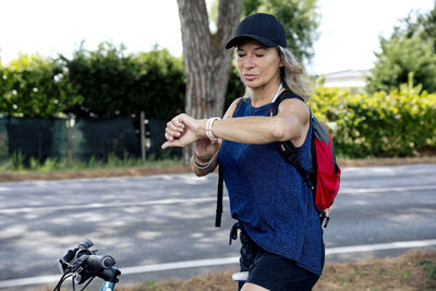 Senior woman on bicycle checking time in smart watch
