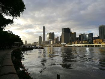 City at waterfront against cloudy sky