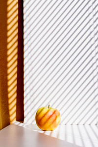 Apple on a white window sill in the sunlight and shadows of the blinds. minimalism. natural product